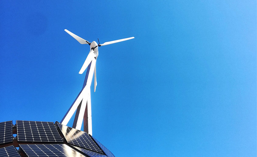 picture of windmill charging solar panels with a bright blue sky background